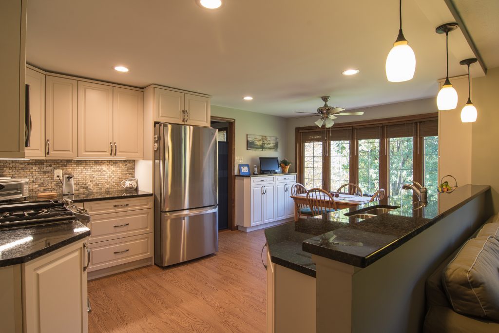 Traditional Style Wexford Kitchen with Raised Panel Door Style Using Warmer Tones on Floor, Countertops and Backsplash.