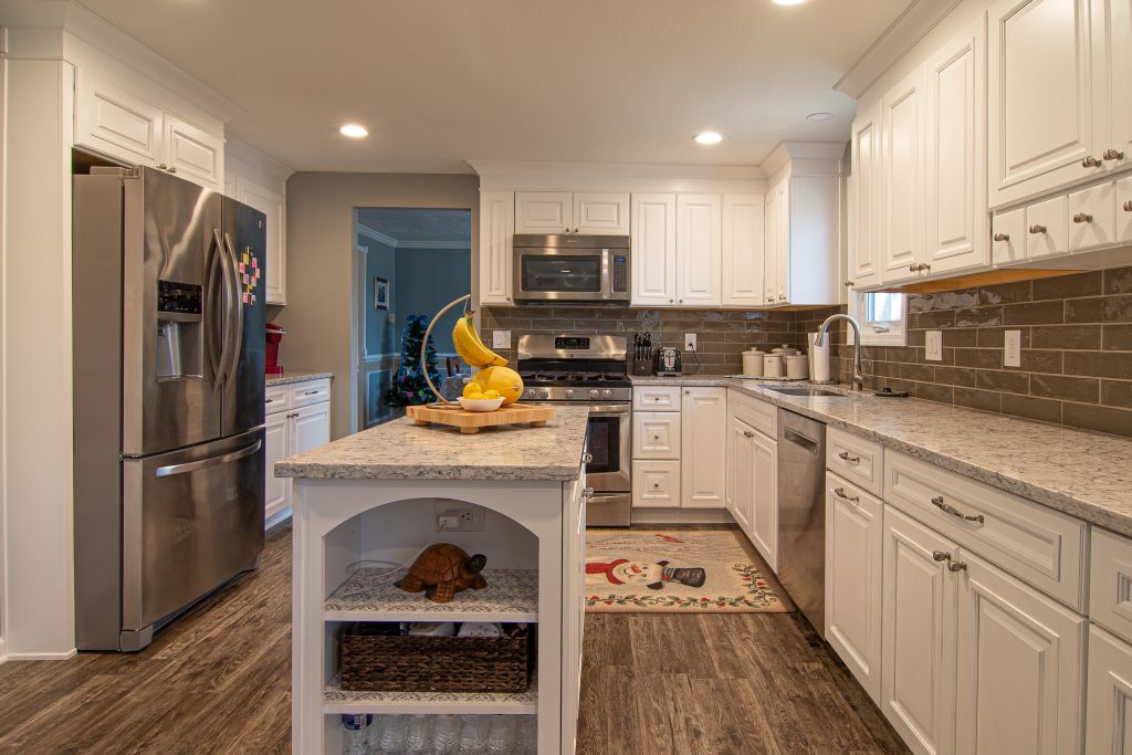 Traditional style Bridgeville kitchen using bright white finish cabinets accented with warm tones on counter tops, backsplash and floor.