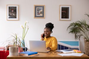 Young African American woman talking on her smart phone and working at home