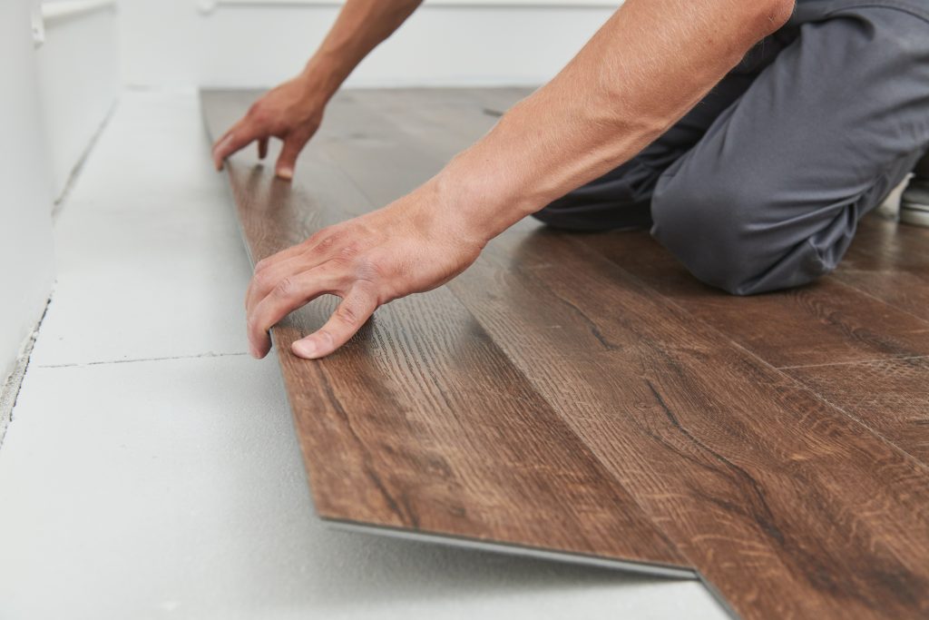 Picture of a man installing new vinyl flooring.