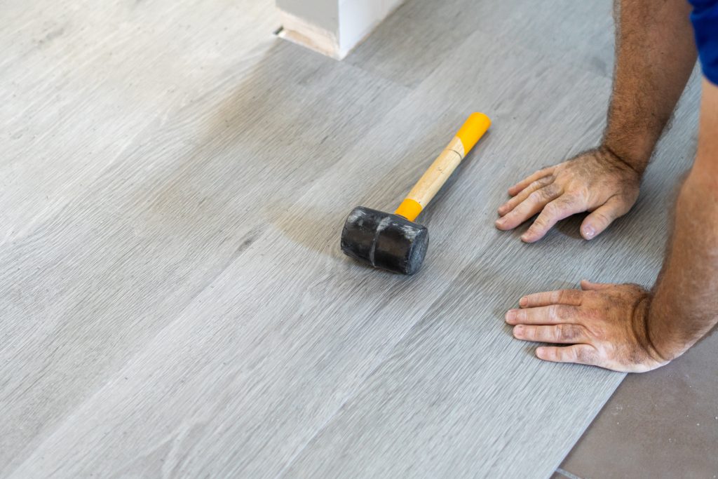 Picture of a technician installing grey vinyl flooring.