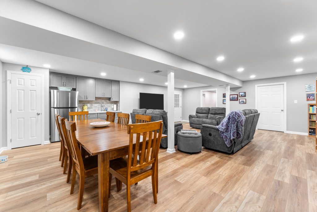 This Monroeville basement boasts a warm living space, a wooden dining table and a kitchenette for that cozy retreat feel.