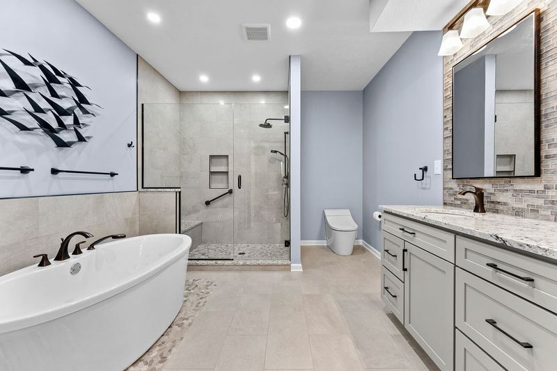 This Contemporary Pittsburgh Master Bathroom with Modern Spa-Inspired Style Utilizing a Freestanding Soaking Tub with Sleek Dark Fixtures, Frameless Glass Walk-In Shower Giving it a Luxurious, Open Feel.