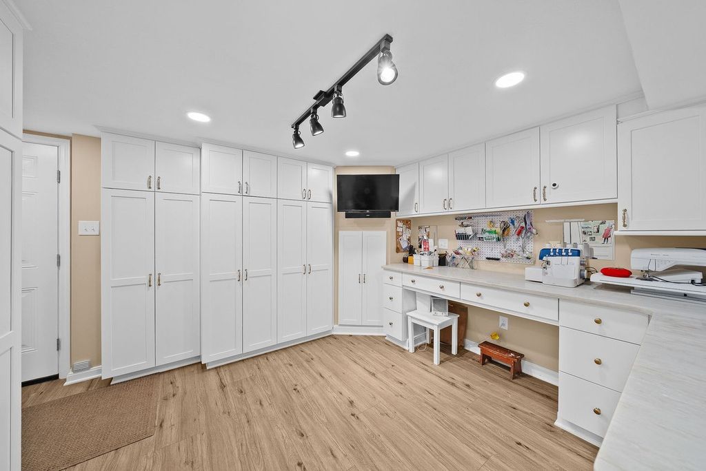 Oakmont Custom Craft Room with Walls of Tall, Built-In White Cabinetry Accented in Gold Offers Extensive Storage for Supplies, Materials and Tools Making it a Motivating Workspace for Sewing, Crafting and Other Creative Projects.