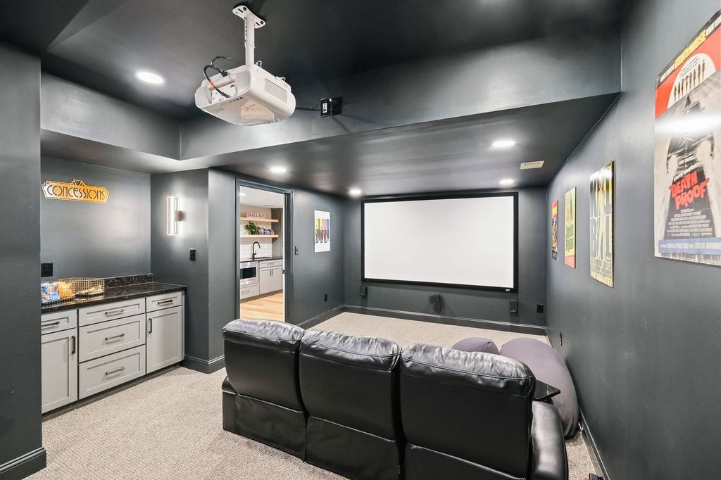 Stylish and Cozy Murrysville Home Movie Theater with Large Screen, Black Leather Couch, Cabinetry, Dark Walls and Light Carpet Creating an Intimate Setting.
