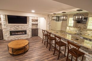 Monroeville basement showing warm colors, straight lined cabinets and stacked stone.